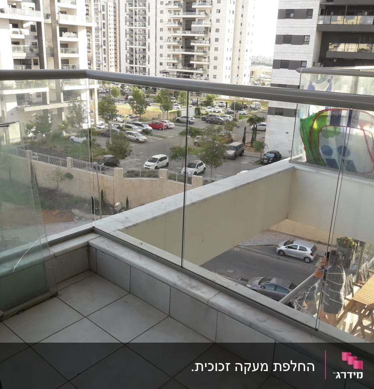 מעקה זכוכית במרפסת עם נוף עירוני